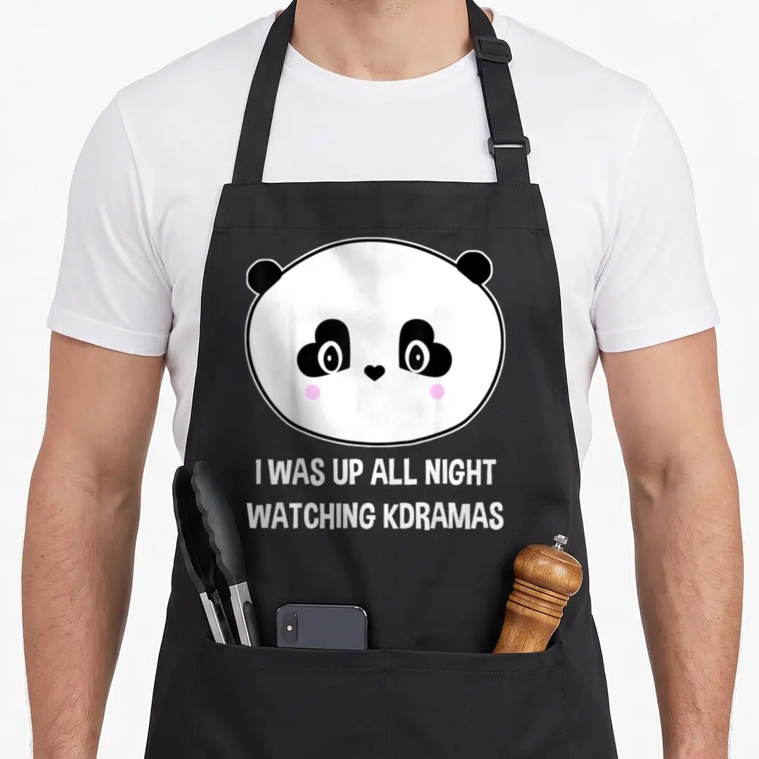 Panda korean apron - Cartoon panda head with heart eyes and text I WAS UP ALL NIGHT WATCHING KDRAMAS — shown on a black cotton canvas apron against a white background