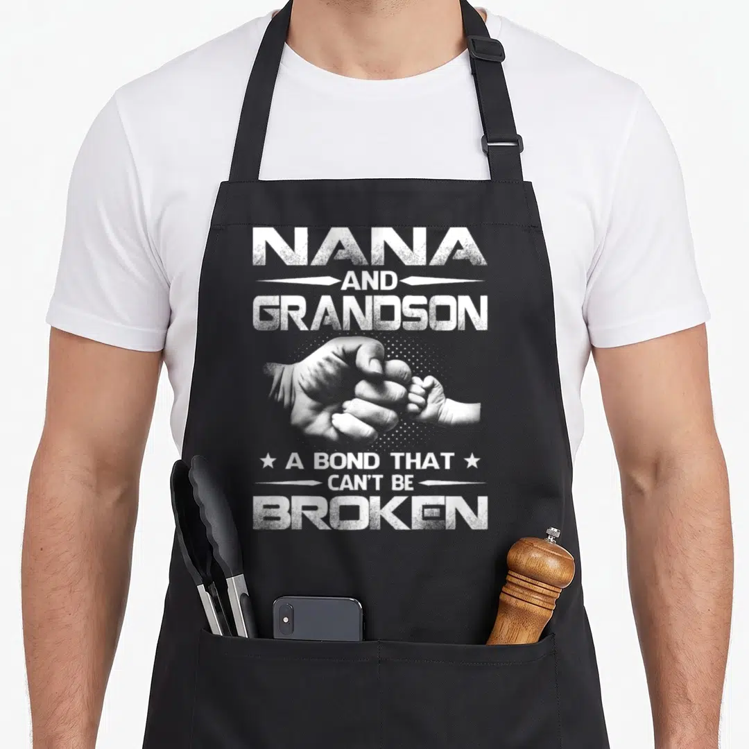 Grandson nana aprons - White distressed text Nana Grandson Bond Broken around clasped hands on black fabric — shown on a black cotton canvas apron against a white background
