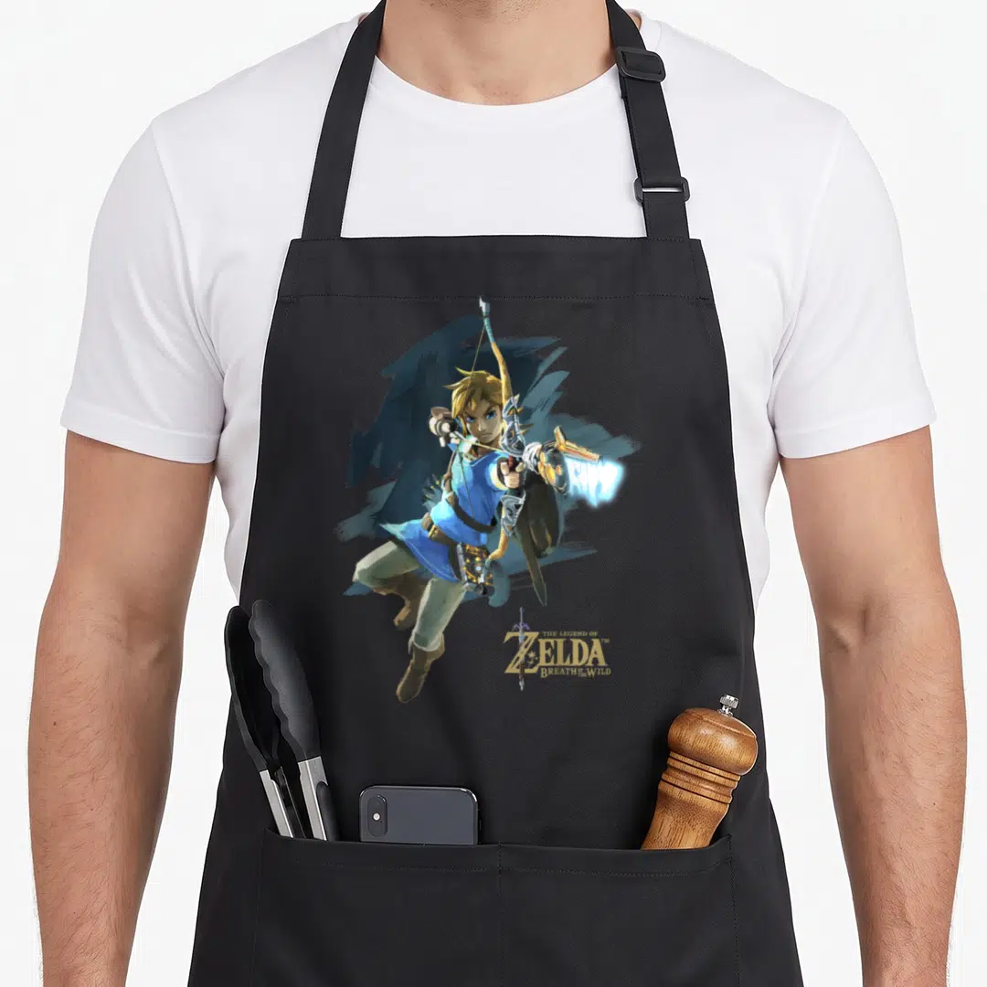 Breath jump apron - Link leaping with bow and shield, gold title text THE LEGEND OF ZELDA BREATH OF THE WILD — shown on a black cotton canvas apron against a white background