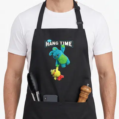 Hang the story of the apron - Blue plush bunny holding yellow chick under IT'S HANG TIME text — shown on a black cotton canvas apron against a white background