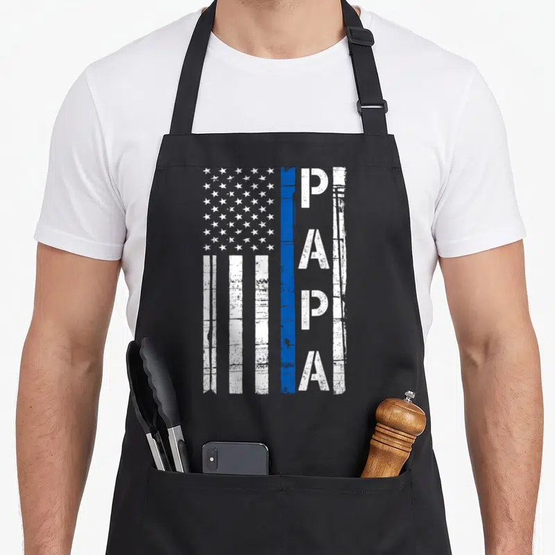 Papa thin american flag apron - Distressed white flag with vertical PAPA text and single blue stripe — shown on a black cotton canvas apron against a white background