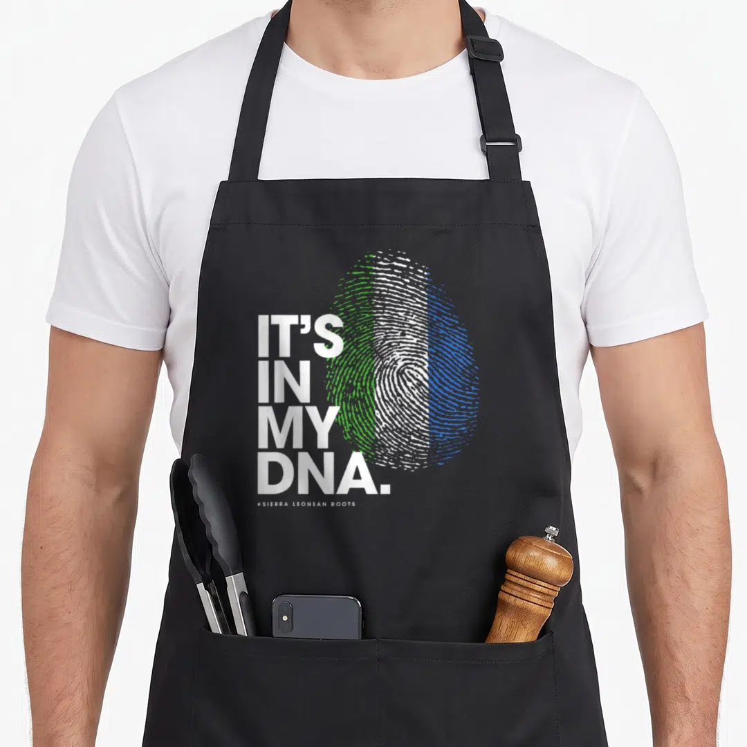 Dna sierra apron - IT'S IN MY DNA text beside fingerprint with white green and blue vertical sections — shown on a black cotton canvas apron against a white background