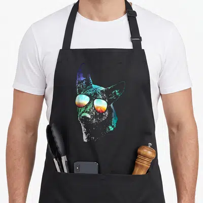 Disco dutch apron - Stylized dog head with sunglasses reflecting a sunset in blue, cyan, orange, and white gradients — shown on a black cotton canvas apron against a white background