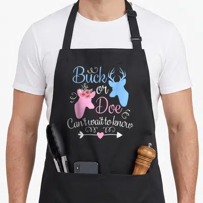 Doe apron or apron - Buck or Doe deer heads blue pink text Can't wait to know heart arrow — shown on a black cotton canvas apron against a white background
