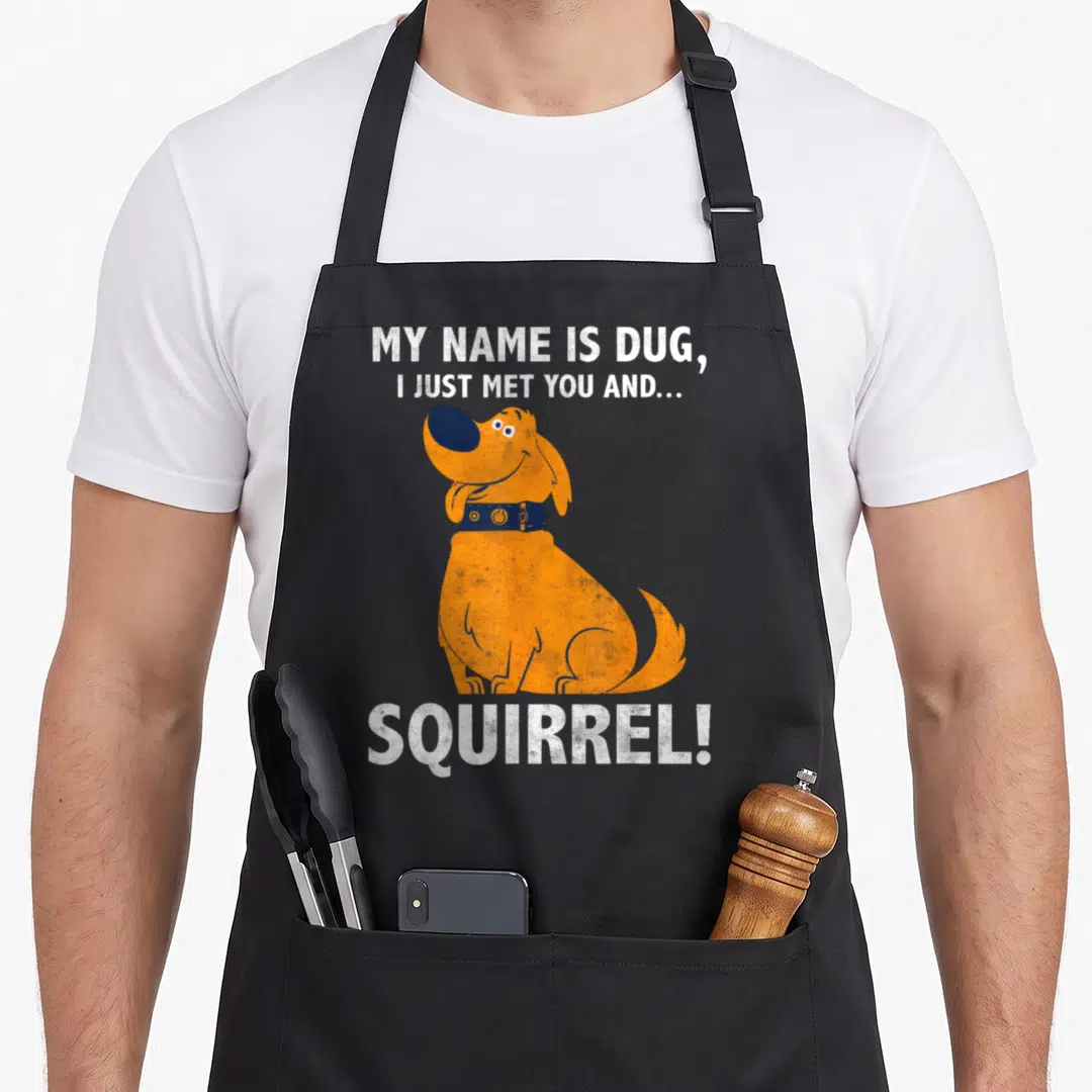 Dug mets apron - Orange dog centered between white distressed text reading My Name Is Dug I Just Met You And Squirrel — shown on a black cotton canvas apron against a white background