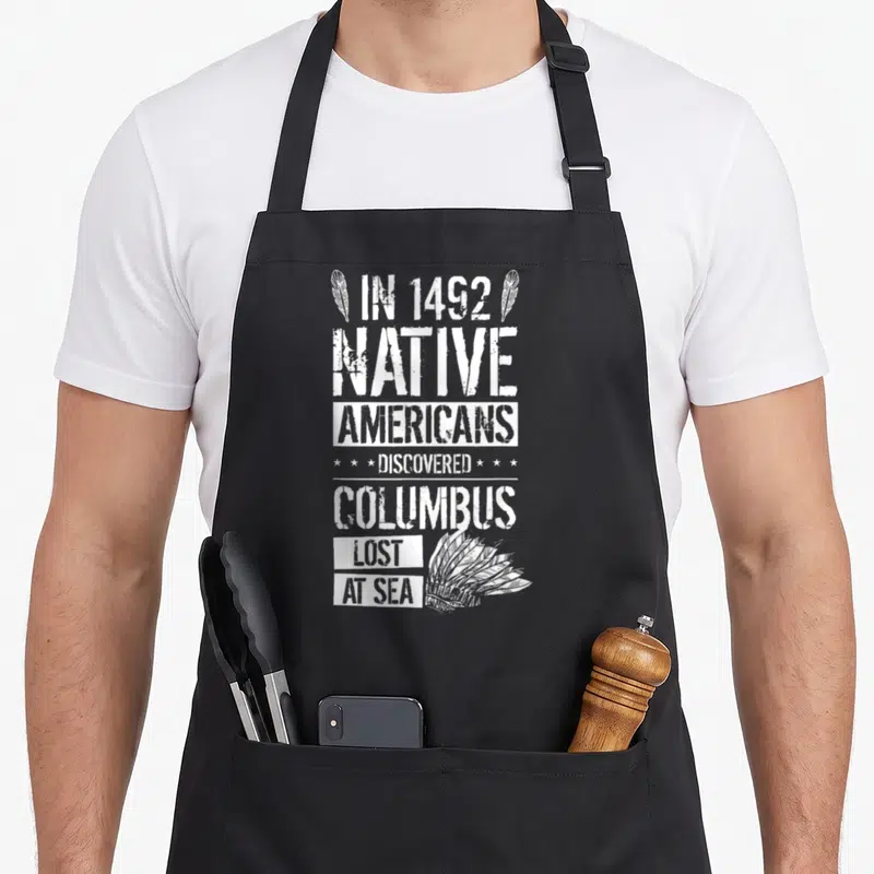 Discovered native american apron - White stacked text reading IN 1492 NATIVE AMERICANS DISCOVERED COLUMBUS LOST AT SEA — shown on a black cotton canvas apron against a white background