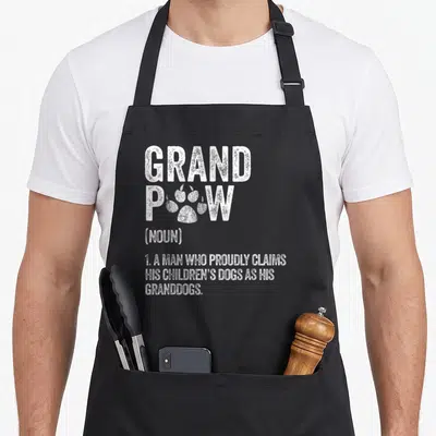 Grandpaw dog themed aprons - White dictionary definition of grandpaw with paw print replacing the letter O — shown on a black cotton canvas apron against a white background