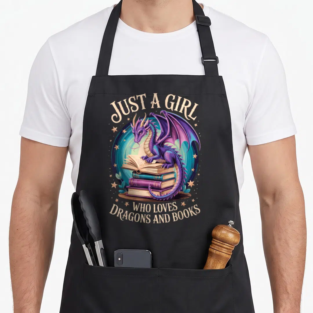 Book bookworm dragon apron - Purple dragon sitting on stacked books with beige text on blue background — shown on a black cotton canvas apron against a white background
