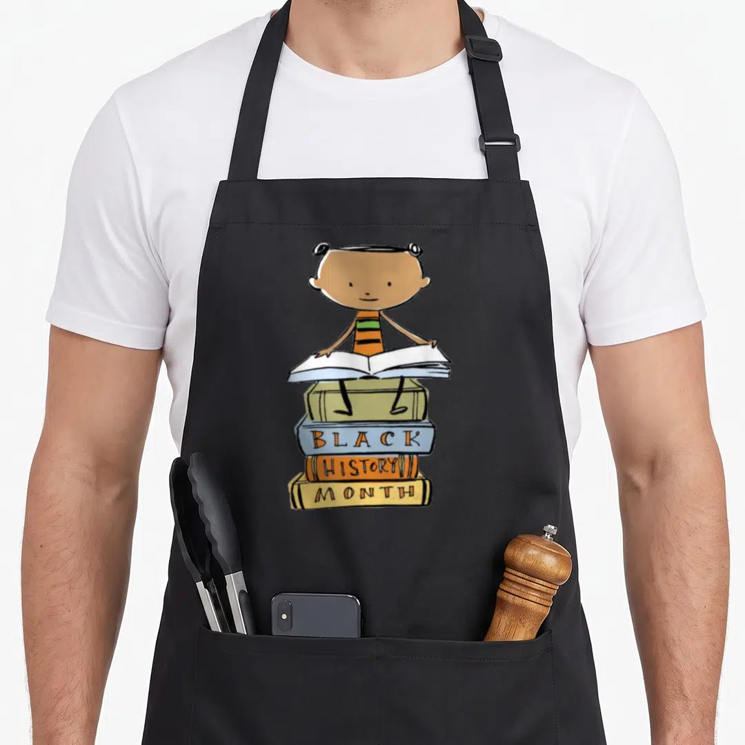 History pride african print apron - Cartoon child on four books with Black History Month text in brown orange blue — shown on a black cotton canvas apron against a white background