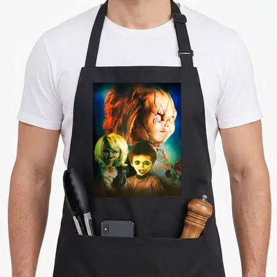 Poster family aprons - Photo print of three dolls with orange hair and blue background — shown on a black cotton canvas apron against a white background