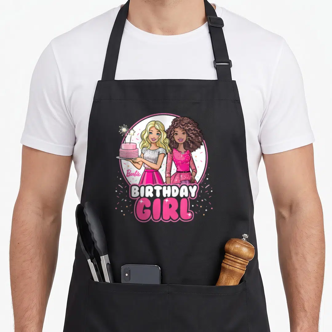 General bday apron - Two cartoon girls in pink circle holding cake with BIRTHDAY GIRL text and confetti — shown on a black cotton canvas apron against a white background