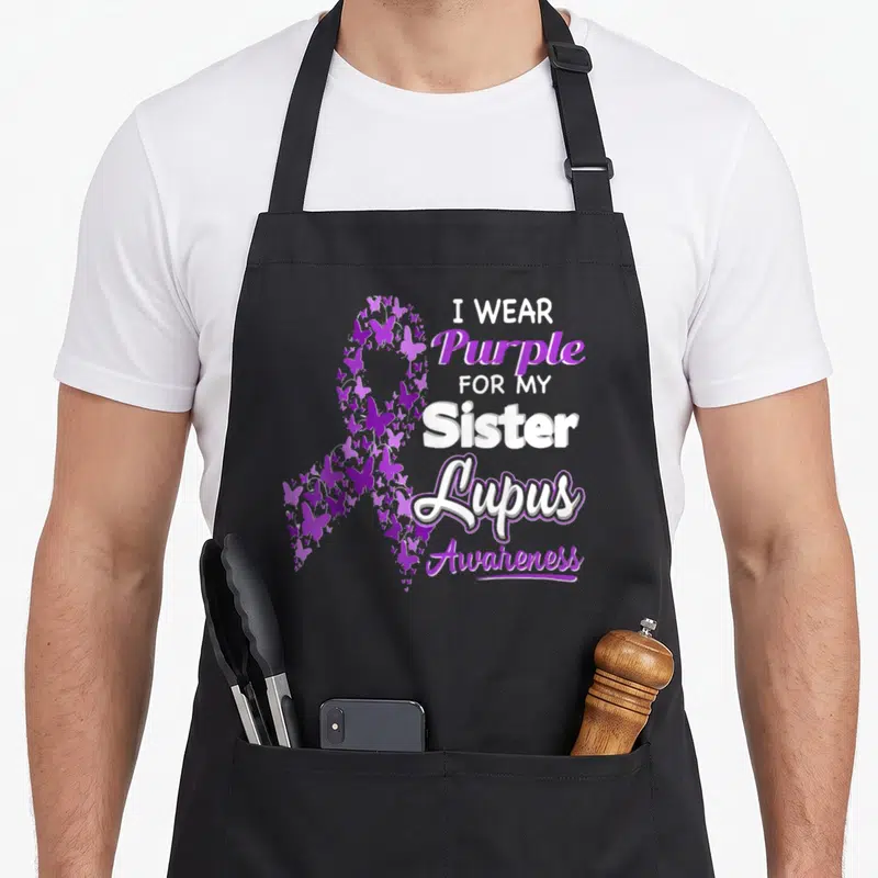 Lupus nun apron - Purple butterfly awareness ribbon and text honoring a sister with lupus — shown on a black cotton canvas apron against a white background