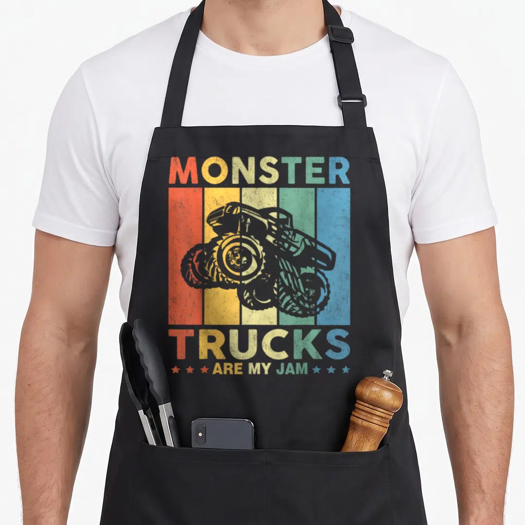 Toddler truck apron - Grey monster truck over five vertical colored stripes with multicolored text reading Monster — shown on a black cotton canvas apron against a white background