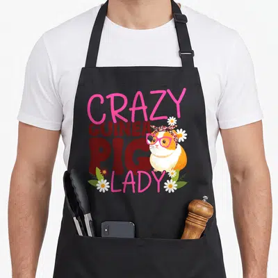 Cool comfort crazy guinea lady apron - Stacked pink and red text reading CRAZY GUINEA PIG LADY beside an orange — shown on a black cotton canvas apron against a white background