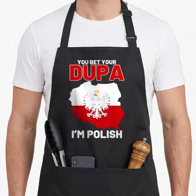Dupa polish kitchen aprons - YOU BET YOUR DUPA I'M POLISH text with Poland map and eagle in red and white — shown on a black cotton canvas apron against a white background