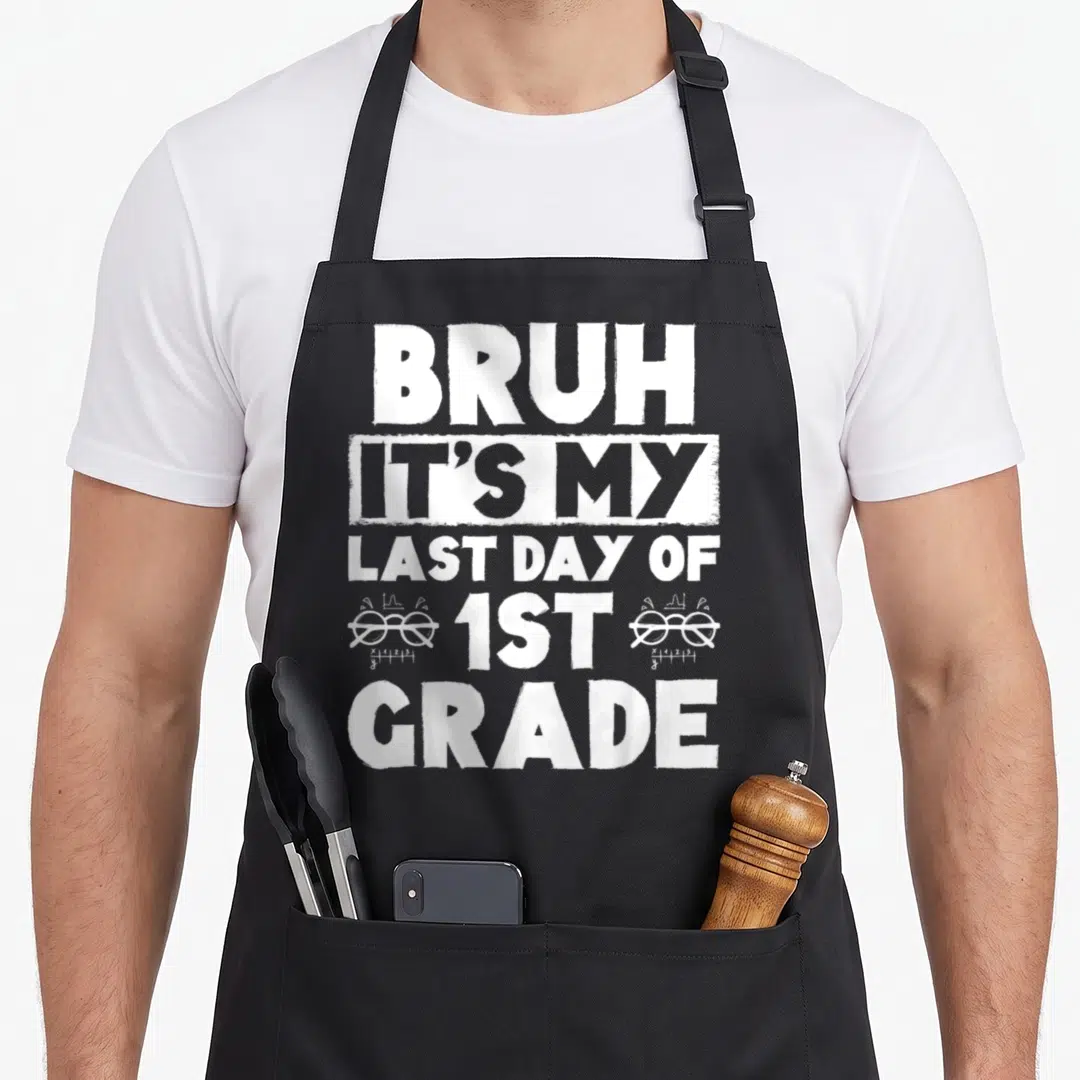 Grade summer teacher apron - Stacked white distressed text reading Bruh It's My Last Day Of 1st Grade with math graphs — shown on a black cotton canvas apron against a white background