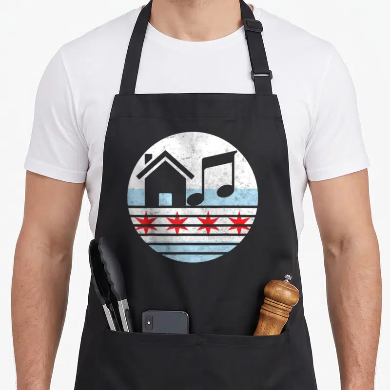 Edm chicago apron - Circular distressed graphic with grey house, musical note, and four red stars on blue and white — shown on a black cotton canvas apron against a white background