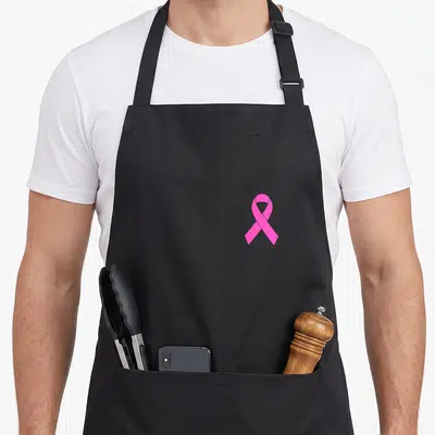 Awareness ribbon apron - Single pink ribbon centered on grey background, minimalist style — shown on a black cotton canvas apron against a white background