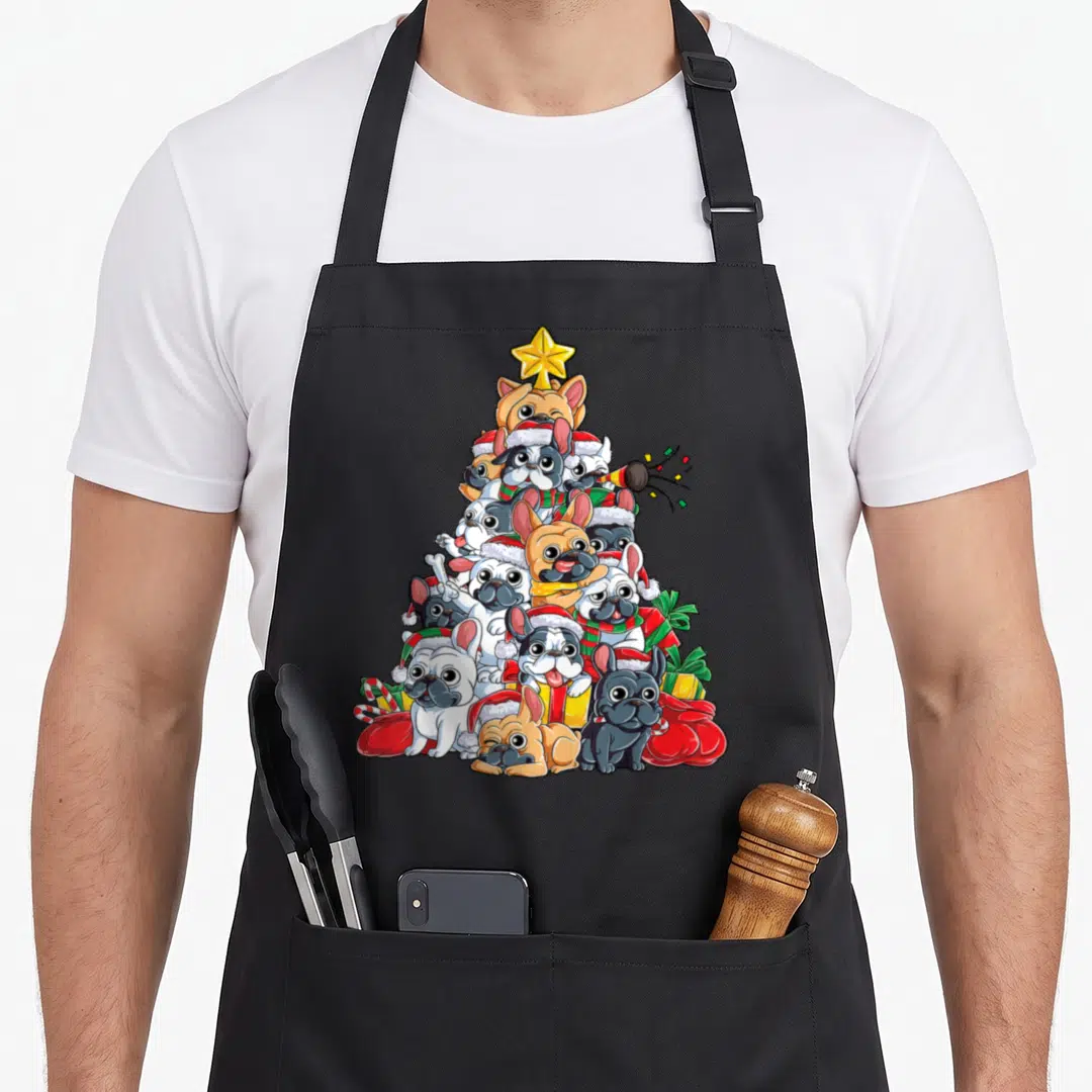 Christmas french apron - Pyramid of French Bulldogs in Santa hats and scarves topped with yellow star surrounded by red — shown on a black cotton canvas apron against a white background