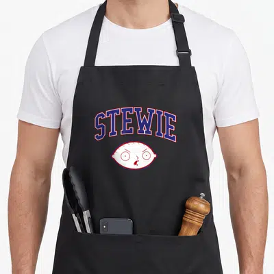 Athletic cartoon apron - Arched STEWIE text in blue and red above a white cartoon baby head with red facial features — shown on a black cotton canvas apron against a white background