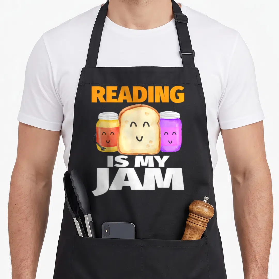 Reading author apron - Cartoon bread and two jam jars with text reading Reading Is My Jam — shown on a black cotton canvas apron against a white background