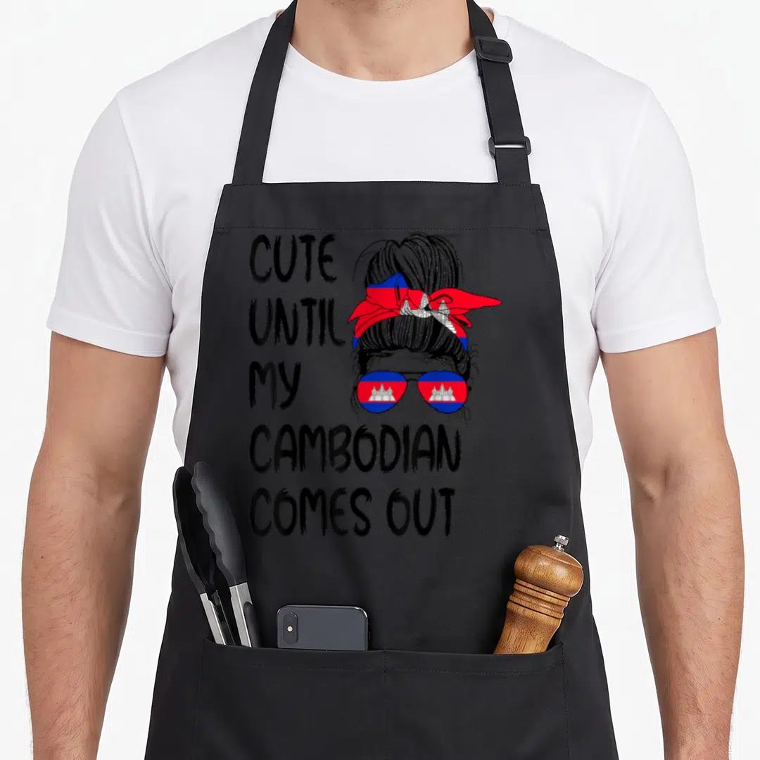 Come cambodian apron - Cute Until My Cambodian Comes Out text next to woman with bun wearing flag bandana and sunglasses — shown on a black cotton canvas apron against a white background