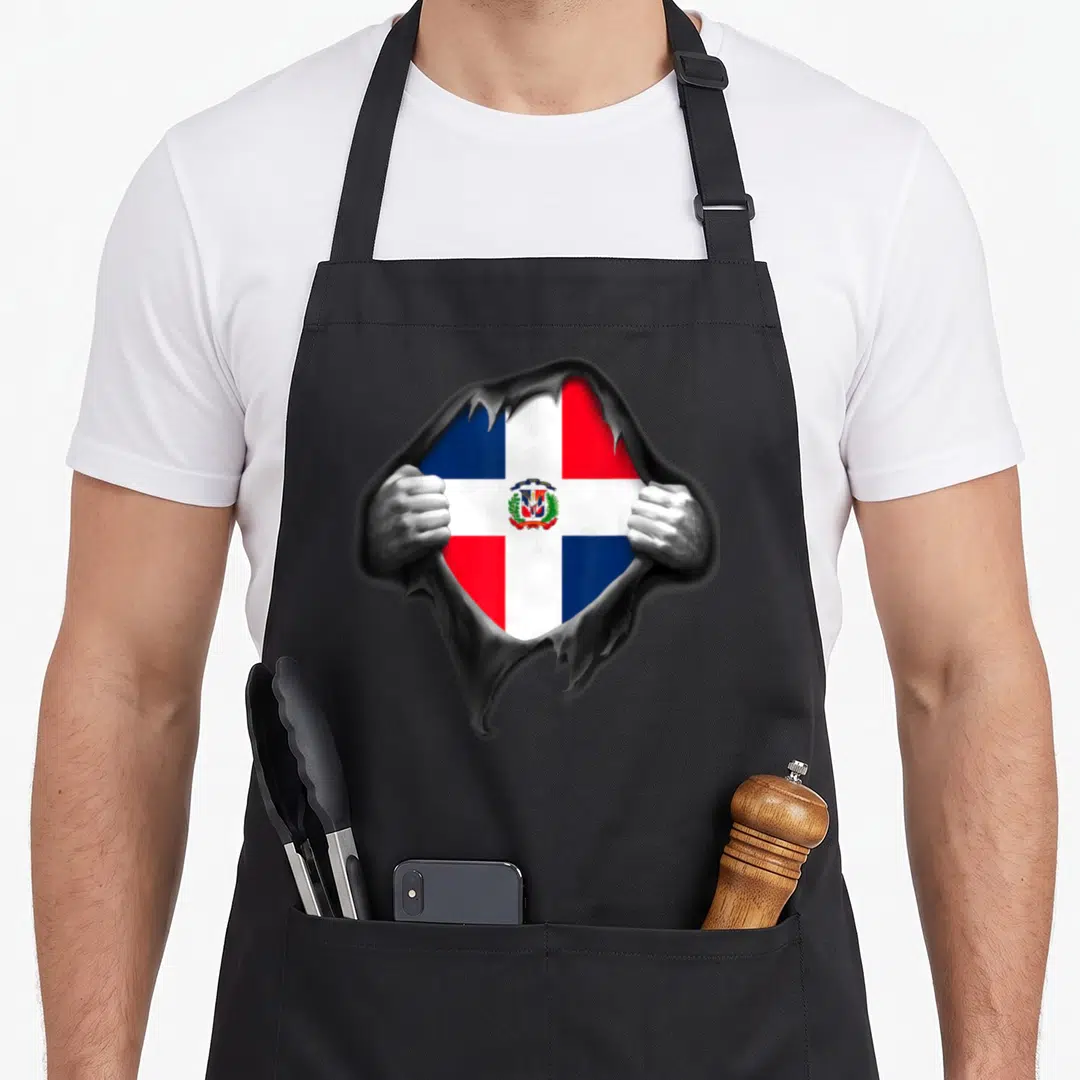 Dominican dominica apron - Flag seen through jagged hole in grey surface with two hands gripping edges — shown on a black cotton canvas apron against a white background