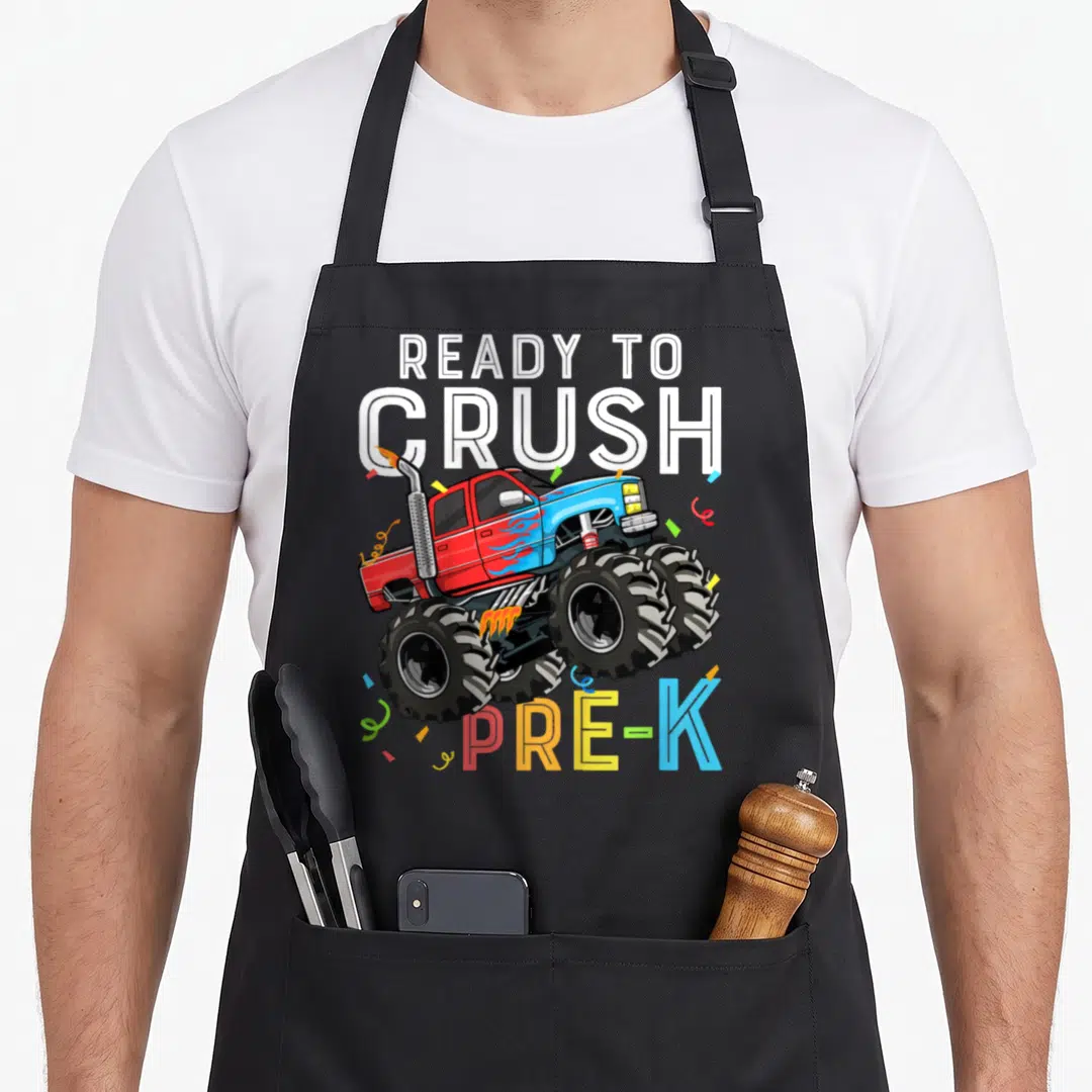Pre preschool truck apron - Cartoon monster truck with confetti and text READY TO CRUSH PRE-K — shown on a black cotton canvas apron against a white background