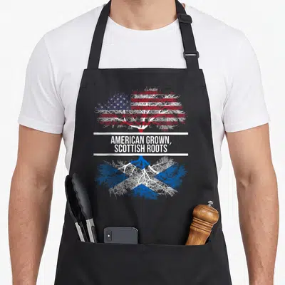 Scottish american flag apron - Tree design with US and Scotland flag patterns split by white band and text — shown on a black cotton canvas apron against a white background