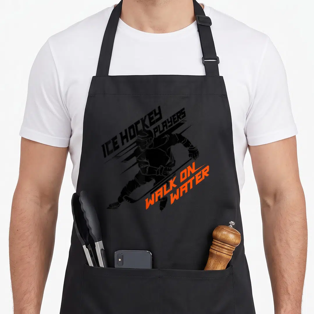 Ice power walking apron - Black cartoon hockey player skating with orange text WALK ON WATER — shown on a black cotton canvas apron against a white background