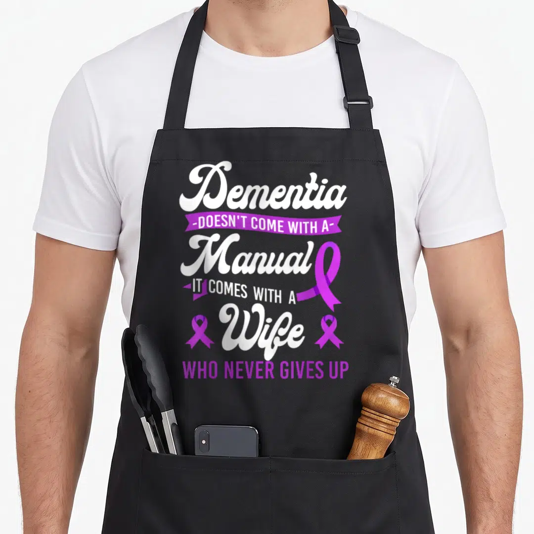 Alzheimer wife apron - White and purple typography reading Dementia Wife with three awareness ribbons — shown on a black cotton canvas apron against a white background