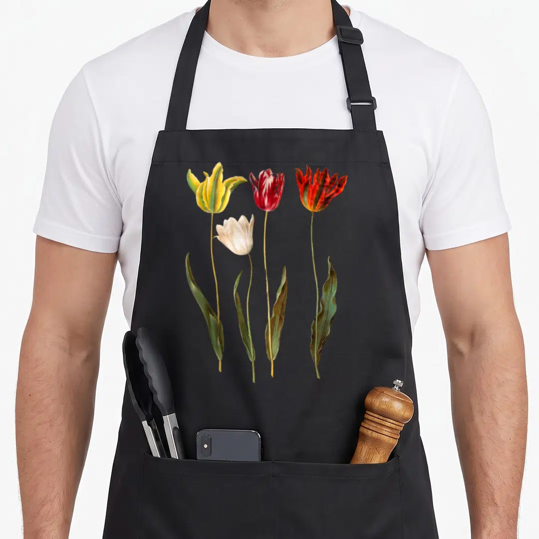 Elegant tulip apron - Four realistic tulips in yellow, red, white, and orange with green stems arranged vertically — shown on a black cotton canvas apron against a white background