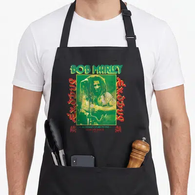Exodus reggae apron - Bob Marley green frame exodus vertical text 1977 Europe Tour distressed print — shown on a black cotton canvas apron against a white background