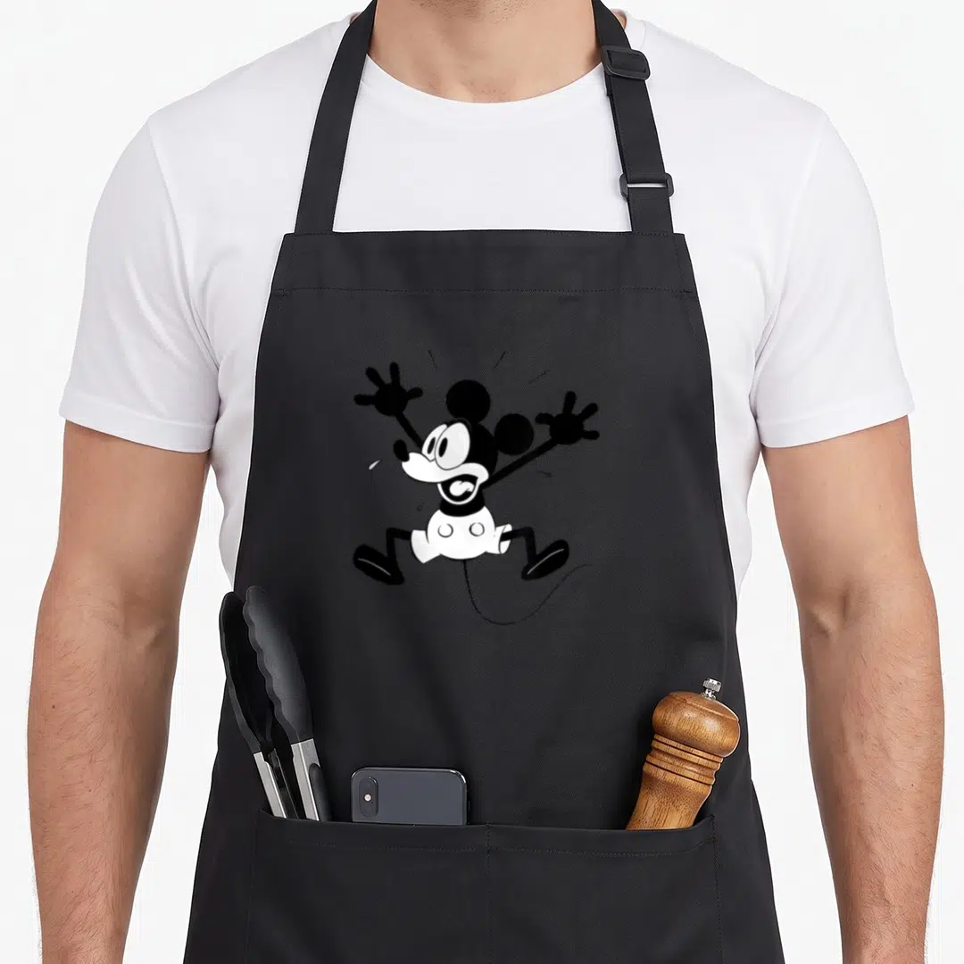 Cute crazy mouse man apron - Black and white cartoon mouse with raised arms and open mouth on grey background — shown on a black cotton canvas apron against a white background