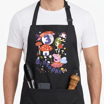 Magical birthday apron - Peppa Pig fairy with 3RD BIRTHDAY text, red mushrooms, and cake stand in pink purple red white — shown on a black cotton canvas apron against a white background