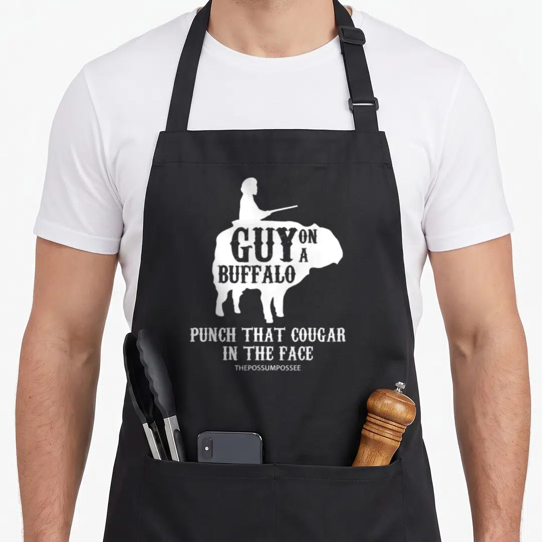 Possum buffalo apron - White silhouette of person riding buffalo with GUY ON A BUFFALO PUNCH THAT COUGAR IN THE FACE — shown on a black cotton canvas apron against a white background
