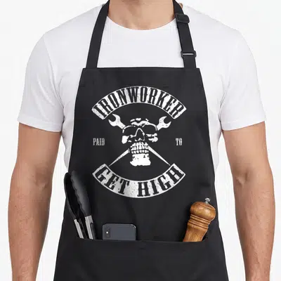 Paid metalworker apron - White distressed skull with crossed wrenches and arched text — shown on a black cotton canvas apron against a white background