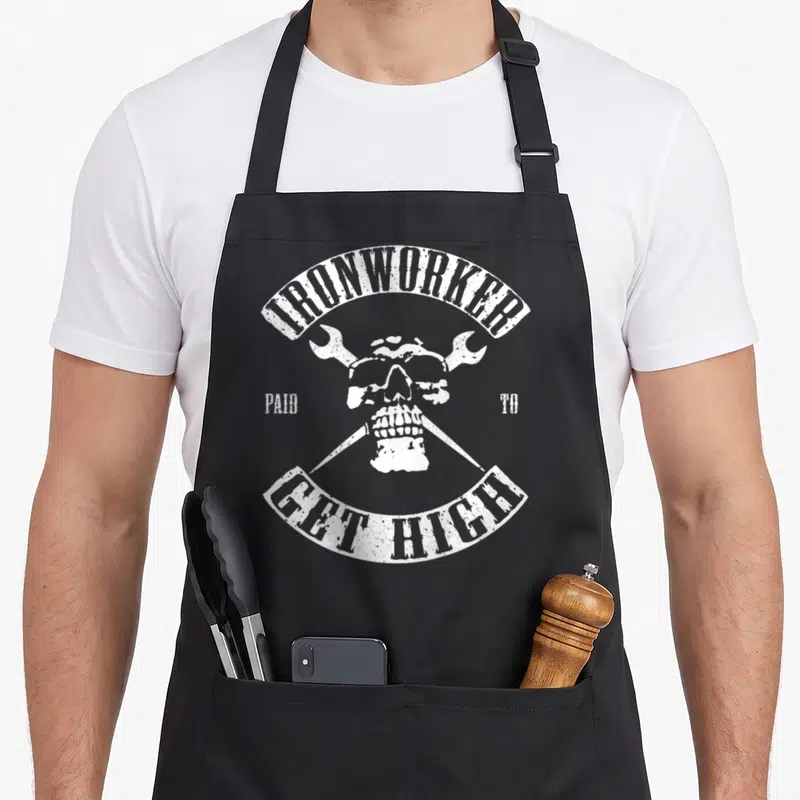Paid metalworker apron - White distressed skull with crossed wrenches and arched text — shown on a black cotton canvas apron against a white background