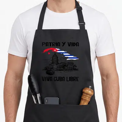 Free cuba libre apron - Distressed Capitolio building and car with Cuban flag shape and Patria Y Vida text — shown on a black cotton canvas apron against a white background