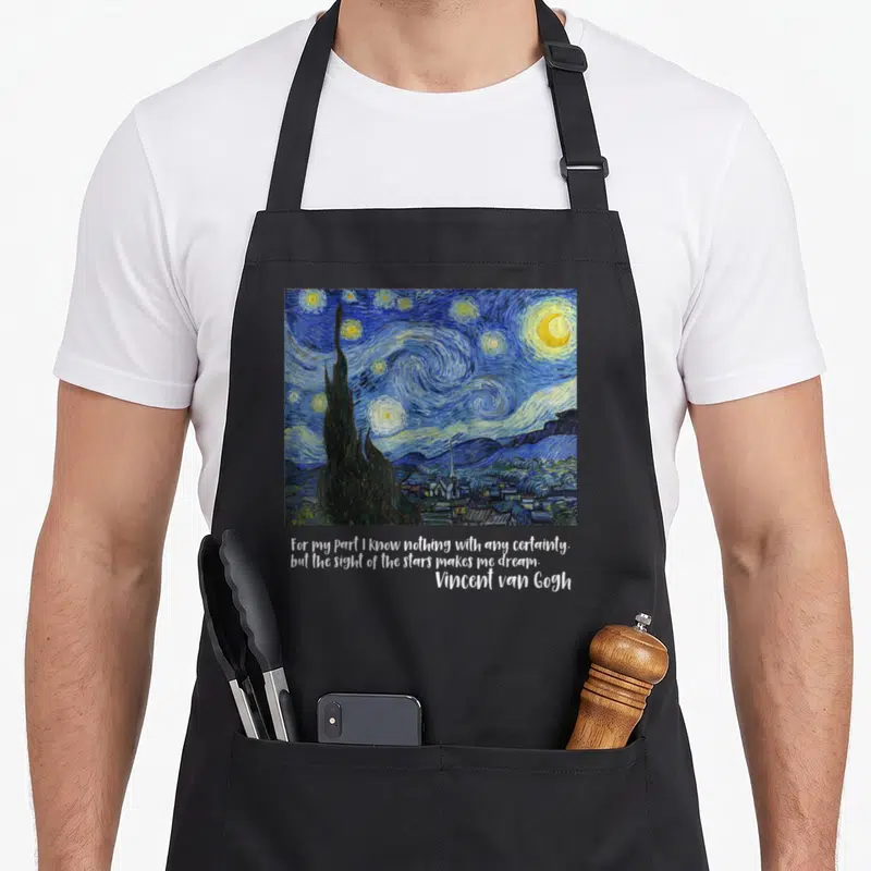 Famous van gogh apron - Starry Night painting print with quote about stars making one dream — shown on a black cotton canvas apron against a white background