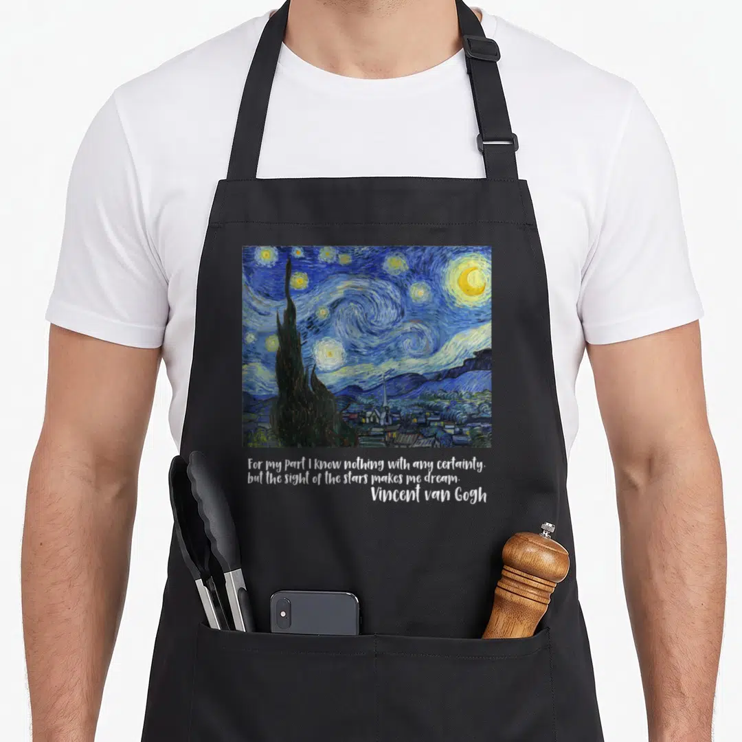 Famous van gogh apron - Starry Night painting print with quote about stars making one dream — shown on a black cotton canvas apron against a white background