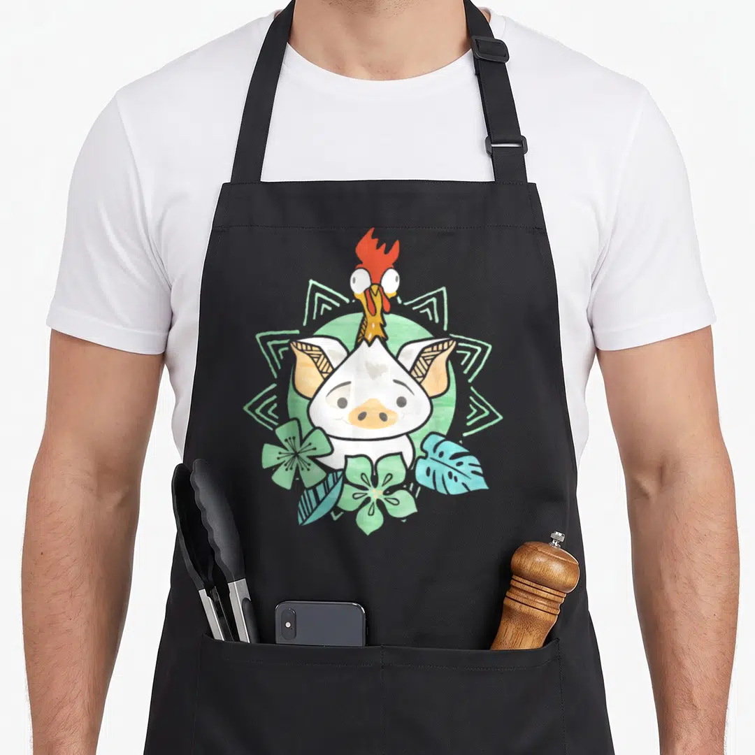 Hei novelty apron - Cartoon pig face with rooster on head, green mandala, teal leaves, white orange green teal — shown on a black cotton canvas apron against a white background