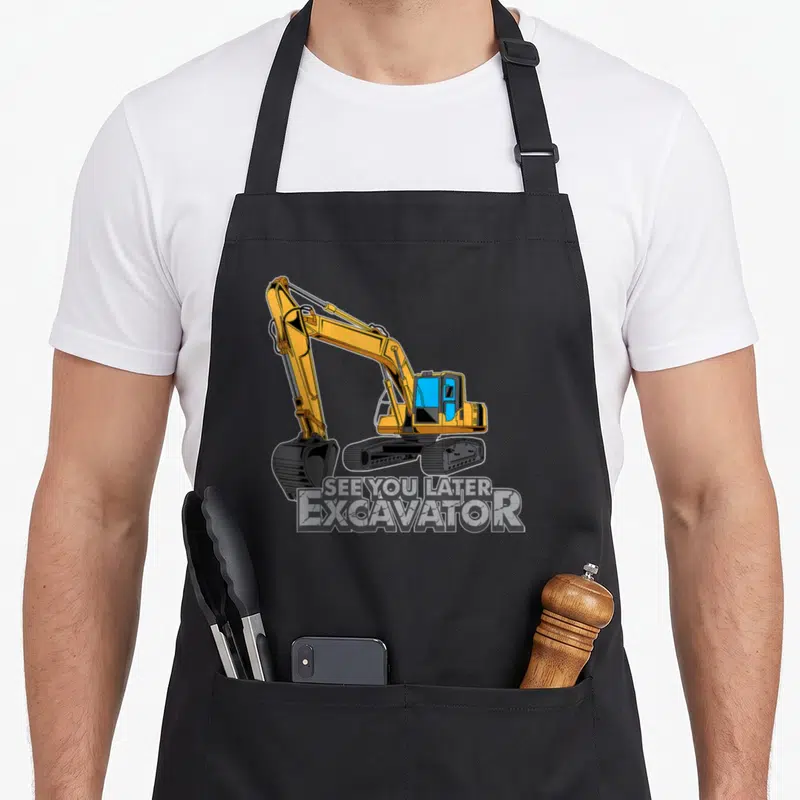 Toddler excavator girl apron - Cartoon yellow excavator above SEE YOU LATER EXCAVATOR text in block letters — shown on a black cotton canvas apron against a white background