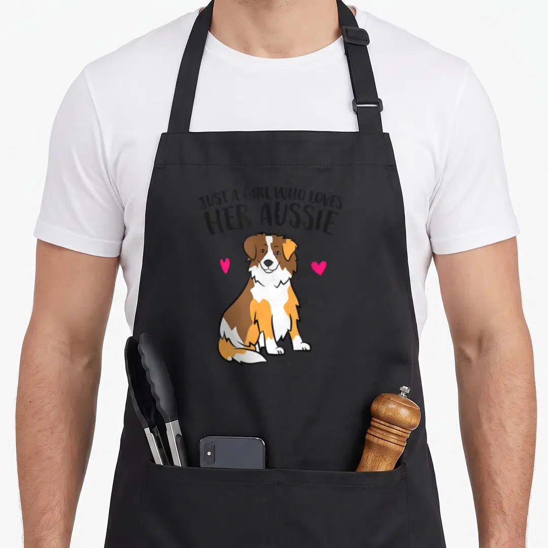Shepherd aussie australian apron - Cartoon Australian Shepherd dog with arched text and two pink hearts on left — shown on a black cotton canvas apron against a white background