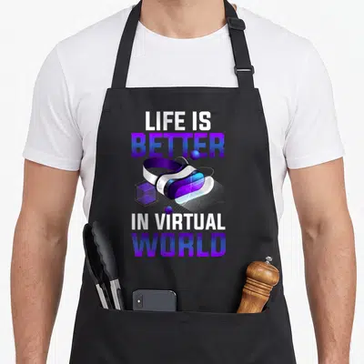 Virtual novelty apron - VR headset graphic with Life Is Better In Virtual World text in purple blue white — shown on a black cotton canvas apron against a white background