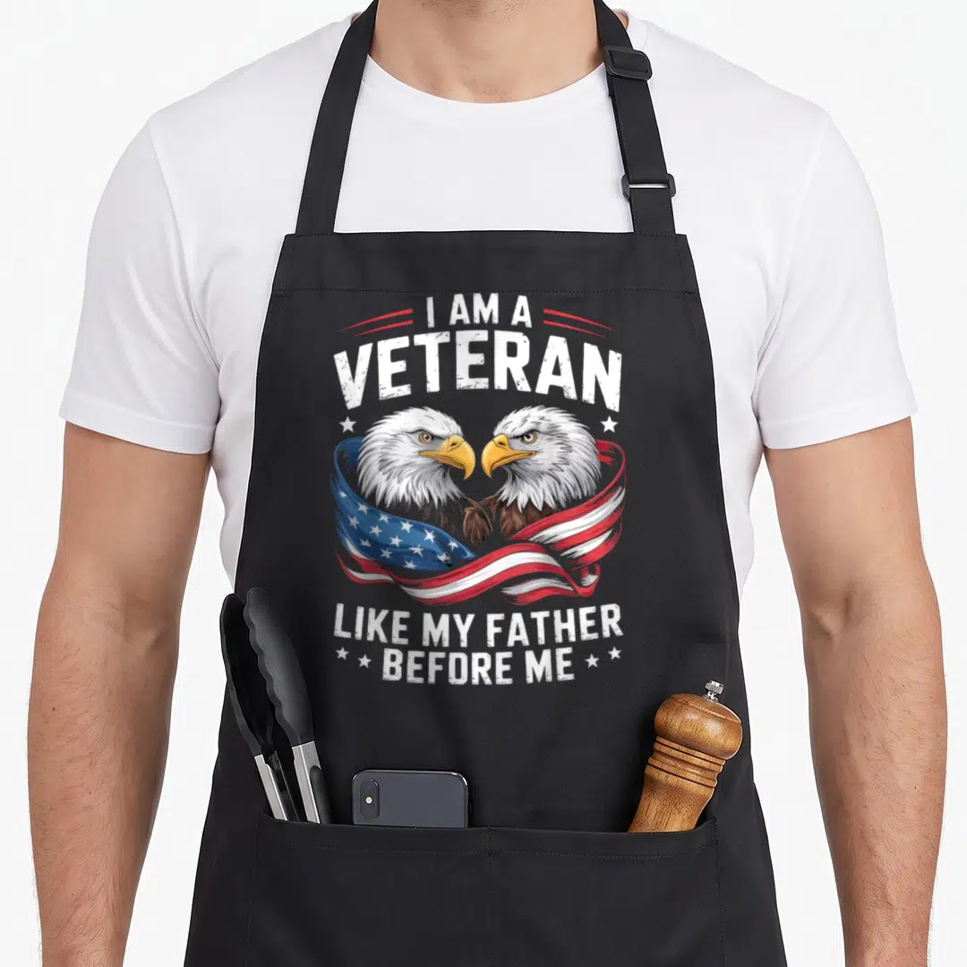 Veteran eagles apron - Two realistic bald eagles wrapped in waving flag with patriotic text — shown on a black cotton canvas apron against a white background