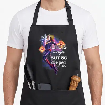 Inspirational captain apron - Captain Marvel photo art with star and text life is tough but so are you in white — shown on a black cotton canvas apron against a white background