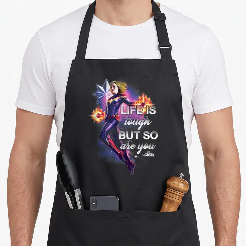 Inspirational captain apron - Captain Marvel photo art with star and text life is tough but so are you in white — shown on a black cotton canvas apron against a white background
