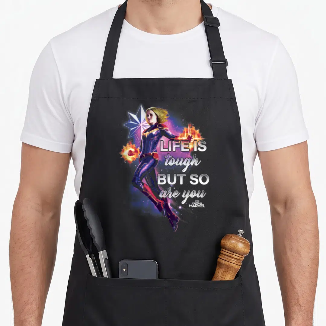 Inspirational captain apron - Captain Marvel photo art with star and text life is tough but so are you in white — shown on a black cotton canvas apron against a white background
