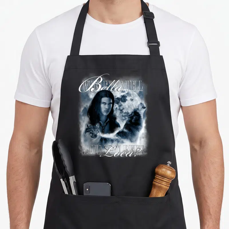 Jacob love swan apron - Man face full moon two wolves blue grey text Where THE HELL Bella HAVE YOU BEEN Loca — shown on a black cotton canvas apron against a white background